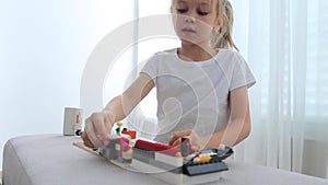 Charming preschooler playing with small constructor. Little girl playing with connecting toy cubes.