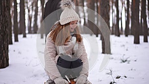 Charming pretty teen girl looking at camera smiling sitting on sled as boy start walking pulling sledge. Tracking shot