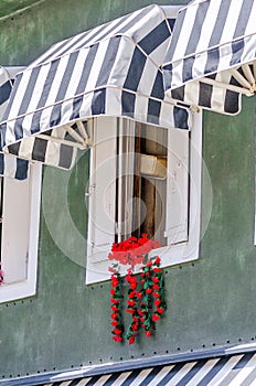 Charming Red Flower Hanging From Old Windowsill in a Rustic Style Building in Parga Town, Greece. Typical Scene Greece.