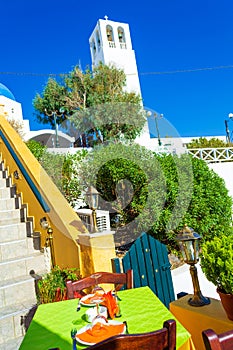 Charming scenery of Thera restaurant table by orthodox church Santorini Greece