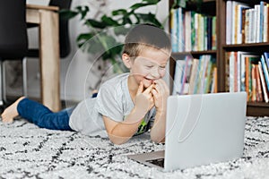 Okouzlující školák chlapec spočívá na patro a hodinky vyučování nebo chatování připojen do internetové sítě přátelé. připojen do internetové sítě studium a 