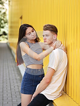 A stunning, sensual portrait of young fashion couple posing on a yellow wall background. Relationship people concept.