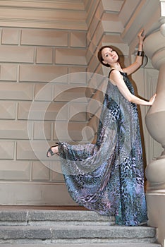 Charming sensual young woman in gauzy lengthy dress on stairs