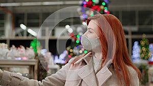 charming shopper wearing face mask buys gifts for family for christmas in department store observing safety rules