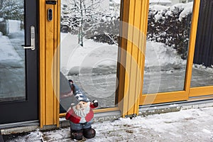 Charming sight of Santa Claus standing in front of entrance door to villa on frosty winter day.