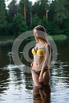 Charming slender girl teenager in fashionable swimsuit standing in water