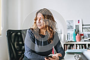 Charming smiling adult woman middle aged woman with curly hair architect designer in the bright modern office