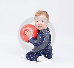 Charming smiling baby holds a red ball