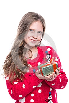 Charming smiling little girl with curly hairstyle wearing red knitted sweater and holding christmas gift isolated on white.