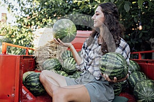 Charming smiling woman in casual clothes tosses watermelon outdoors photo