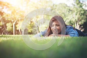 Charming smiling young hipster woman lying on green grass.