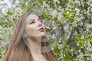 Charming spring woman fashion beauty portrait. Young model with make-up and long hair in blossom garden