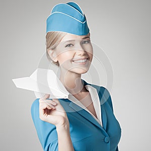 Charming Stewardess Holding Paper Plane In Hand. Gray Background