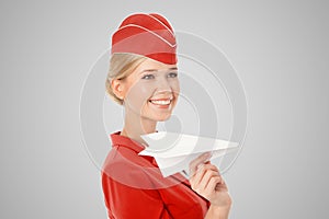 Charming Stewardess Holding Paper Plane In Hand. Gray Background