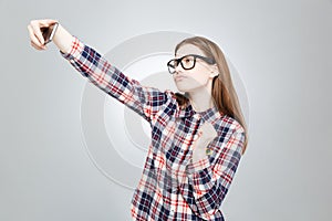 Charming teenage girl in glasses taking selfie with cell phone