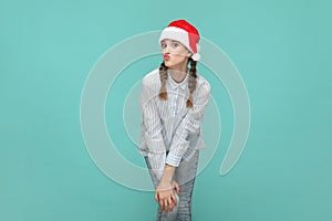Charming teenager girl in Santa Claus hat, looking at camera with pout lips, sending air kissing.