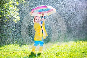 Charming toddler with umbrella playing in the rain