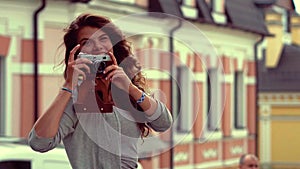 Charming tourist girl with old camera taking pictures in the street,