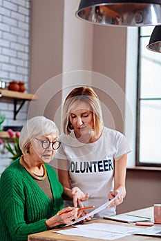 Charming volunteer explaining granny how to correctly fill in application