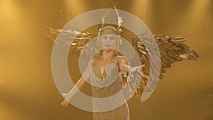 A charming woman actress in the image of the Greek goddess Artemis with golden wings sings and dances on stage