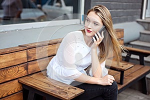 Charming woman with a beautiful smile speaks good news on a mobile phone while relaxing in a cafe, a happy Caucasian