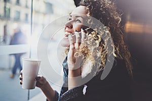 Charming woman with beautiful smile using mobile phone during rest in coffee shop. Blurred background.