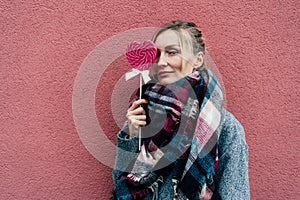 Charming woman with big heart-shaped caramel pink lollipop.