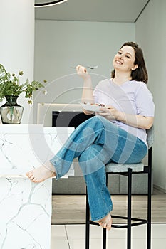 Charming woman eating vegetable salad in modern kitchen