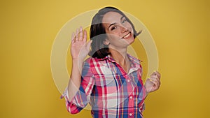 Charming woman expressing tenderness and saying good bye in plaid shirt on a yellow background. Facial expressions