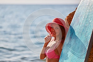 Charming woman in hat on ocean background, copy space. Beach day, summer time, holiday trip and surfing sport concept