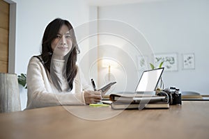 Charming woman holding smart phone and smiling to camera.