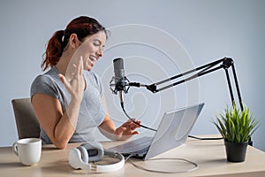 A charming woman radio host is broadcasting live on a laptop. Online radio concept