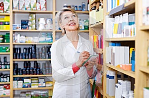 Charming woman seller writing down care products in shop
