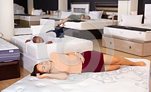 Charming woman sleeping on a new mattress in furniture store