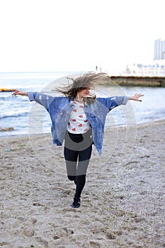 Charming woman with smile poses and walks along sea shore on war