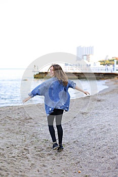 Charming woman with smile poses and walks along sea shore on war