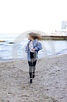 Charming woman with smile poses and walks along sea shore on war