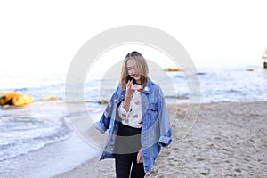 Charming woman with smile poses and walks along sea shore on war