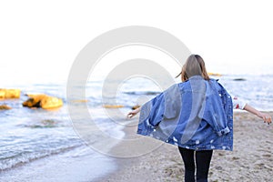 Charming woman with smile poses and walks along sea shore on war