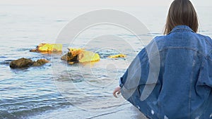 Charming woman with smile poses and walks along sea shore on warm summer evening.