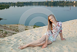 Charming woman smiles on sand near town lake