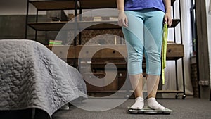 Charming woman standing on scale measuring weight