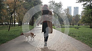 Charming woman texting on phone while walking dog