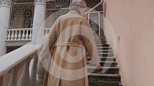 Charming woman walking up stairs. Tracking shot of cute female in coat.