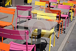 Charming yellow orange and pink chairs on cafe outdoor restaurant cafe and wooden tables colorful terrace