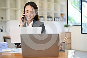 Charming Asian businesswoman or female secretary talking on the phone with business partner