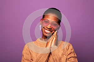 Charming young black woman 20s wears beige sweater over purple background