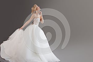 Charming young bride in luxurious wedding dress. Pretty girl in white. Emotions of happiness, laughter and smile, gray