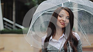 Charming young business woman in hat walking with umbrella along the street of an old town. Beautiful girl is happy, she