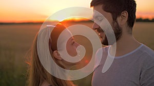 Charming young couple kissing in wheat field at sunset